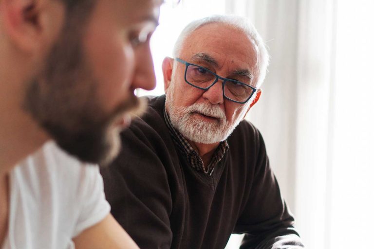 A younger man talking with an older man, both looking concerned